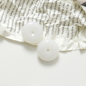 Detailed macro view of two white jade-style round charms on vintage book pages