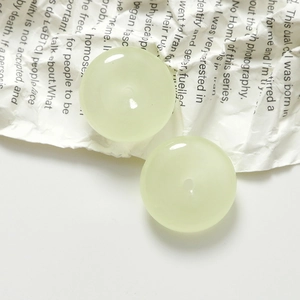 Detailed macro view of two light green resin round charms with center holes for DIY jewelry