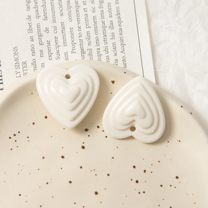 Gros plan de pendentifs en forme de cœur étagés crème sur plateau pour bijoux DIY