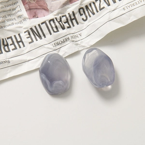 Vue détaillée macro de deux pendentifs en résine marbrée sur un fond de papier texturé
