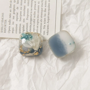 Detalle de pendientes de resina hechos a mano con flores secas, pan de oro y degradado