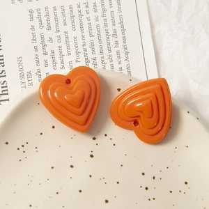 Gros plan de pendentifs cœur en acrylique orange triple couche pour bijoux DIY