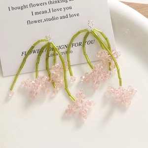 Détail de boucles d'oreilles fleurs en perles de cristal rose et pampilles de vigne verte