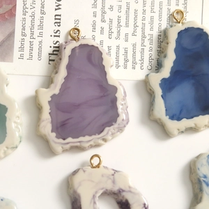 Detalle de colgantes de resina jaspeada irregular con anillos dorados para joyería DIY