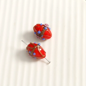 Macro detail of red handmade glass bead with floral motifs and gold powder accents