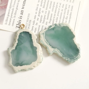 Detalle de colgantes de resina de mármol verde esmeralda con lazo dorado para joyería