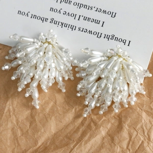 Élégantes boucles d'oreilles en perles et cristaux disposées sur un papier texturé