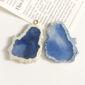 Detalle de colgantes de resina irregulares con textura de mármol azul y aros dorados