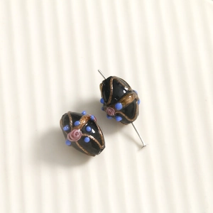 Detailed macro view of black lampwork glass beads with hand-painted gold dust and roses