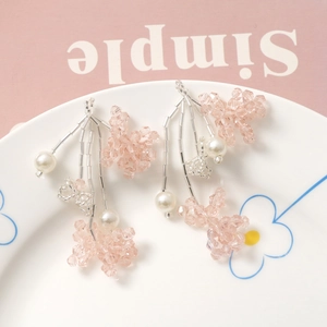 Pink handmade beaded flower earrings with fringe tassels and white pearls on white plate