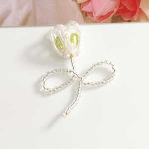 Detailed view of handmade beaded tulip flower charms in white and soft green acrylic
