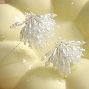 Gros plan de boucles d'oreilles avec perles blanches en goutte et cristaux à facettes