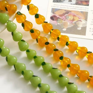 Macro shot of 3D glass pear beads with green leaf accents for creative DIY jewelry crafts