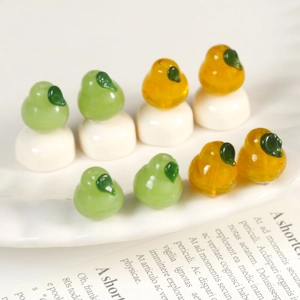 Macro detail of realistic pear-shaped glass beads in green and yellow with leaf accents
