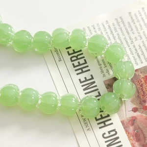 Macro shot of translucent light green pumpkin shaped resin beads for jewelry making