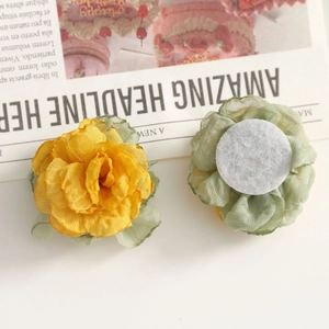 Detalle de rosas de tela amarilla con hojas de malla y base de fieltro para manualidades