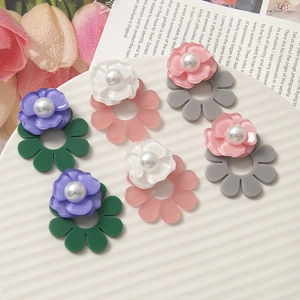 Orecchini a fiori in acrilico con perle finte in vari colori su piatto bianco