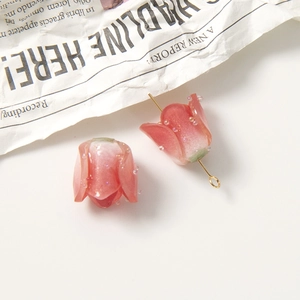 Detail of pink resin rosebud charms with glitter and golden metal ring attachment