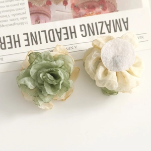 Detalle de rosas de tela hechas a mano con pétalos de organza y base de fieltro blanco