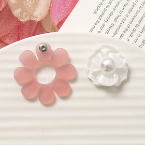 Macro di orecchini a fiore in resina con perle e glitter su vassoio bianco