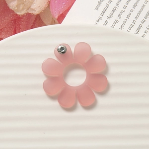 Dettaglio di orecchini a fiore in acrilico rosa opaco su un piatto in ceramica decorato