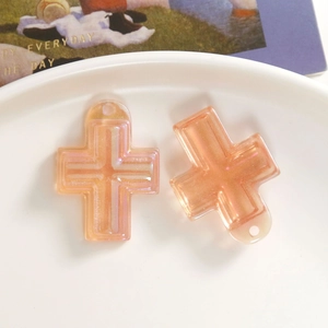 Detail von schimmernden orangefarbenen Kreuzanhängern mit Ösen für DIY-Schmuckprojekte