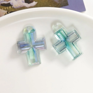 Detail von blaugrünen Marmor-Resin-Kreuzanhängern mit Löchern in einer weißen Keramikschale