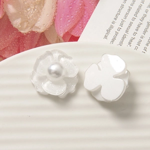 Dettaglio di ciondoli a fiore in acrilico bianco con centri di perle e finiture brillanti