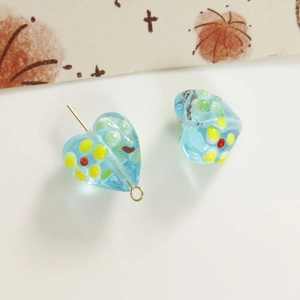 Macro detail of sky blue glass heart beads with colorful floral patterns for DIY jewelry
