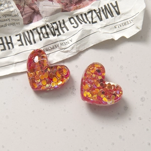 Nahaufnahme herzförmiger Harz-Accessoires mit rosa Glitzer und Goldpailletten für DIY-Basteln