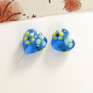 Macro shot of blue heart-shaped lampwork glass beads with floral patterns for DIY jewelry