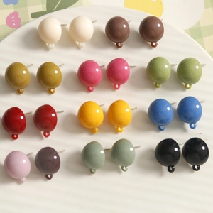 Close-up of colorful resin bead earrings with hanging loops on a white textured plate