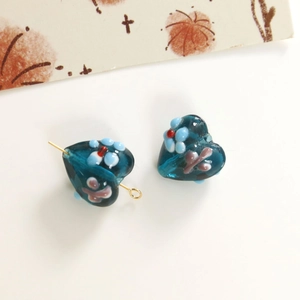 Macro shot of handmade heart-shaped glass beads with blue floral patterns for DIY jewelry