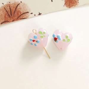 Close-up of pink heart-shaped glass beads with floral patterns for DIY jewelry making