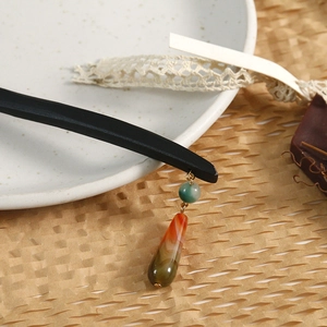 Detail of sandalwood hairpin with turquoise beads and carnelian drops on ceramic