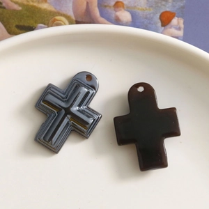 Makro-Detail von geometrischen AB-Harz-Kreuzanhängern in Schwarz und Braun für DIY-Schmuck
