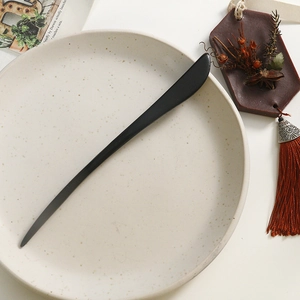 Minimalist black wooden hair pin on a ceramic plate with dried flowers for hanfu styling
