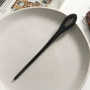 Detail of a minimalist black sandalwood hair pin with a hollow teardrop design on ceramic