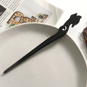 Close-up of a carved black sandalwood hair pin placed on a vintage ceramic plate