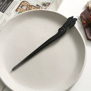 Macro shot of hand-carved black sandalwood hair pin with traditional hollowed cloud motif