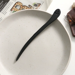 Detailed close-up of a vintage black ebony hair stick with elegant flower hollow carving
