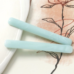 Detail shot of light blue resin hair clips featuring soft marble texture and minimalist design