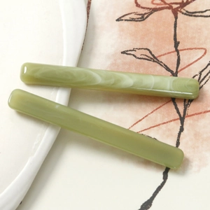 Detailed view of light green resin hair clips with marble patterns and smooth edges