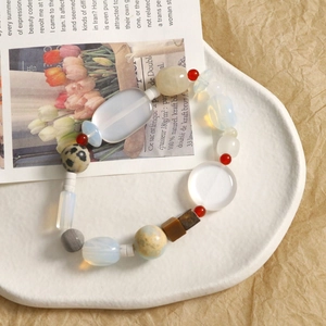 Detail shot of mixed stone beads in a white ceramic dish for DIY jewelry making