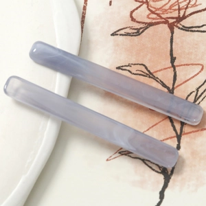 Close-up of lavender acetate hair clips with marble texture on elegant white ceramic