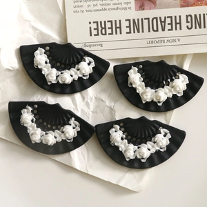 Detailed macro view of four black and white fan-shaped resin flower jewelry accessories
