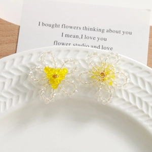 Gros plan de boucles d'oreilles fleurs en perles de cristal sur un plateau en céramique