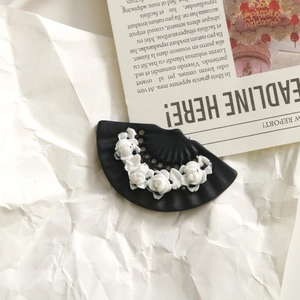 Detail view of dark matte fan-shaped hair clip with elegant white resin rose flowers