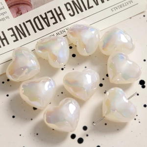 Close-up of iridescent heart-shaped acrylic beads with pre-drilled holes for DIY jewelry