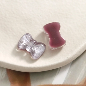 Macro shot of glittery purple and pink resin bow charms for DIY jewelry and hair accessories